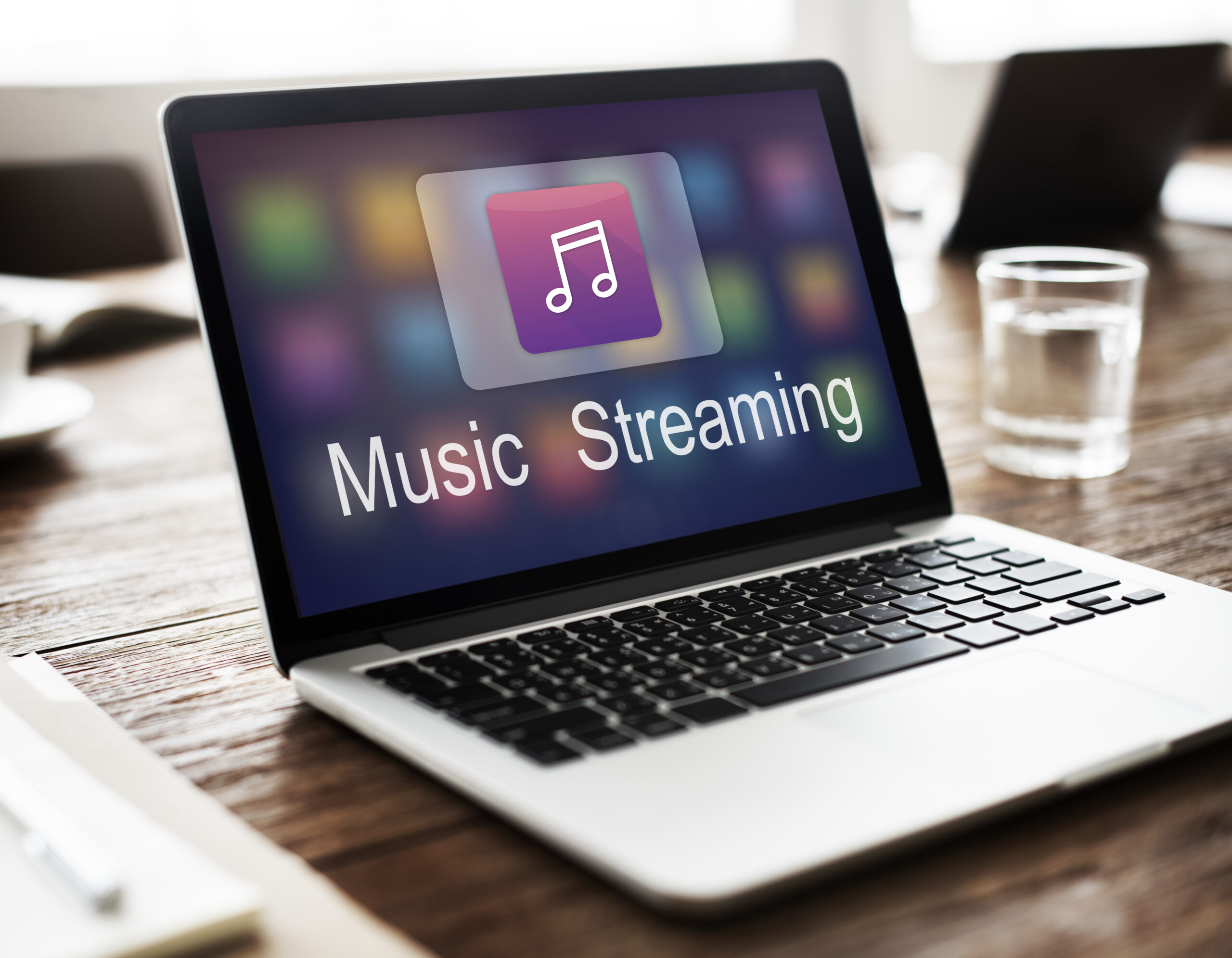 Laptop on a Wooden Desk Displaying a Music Streaming App on the Screen