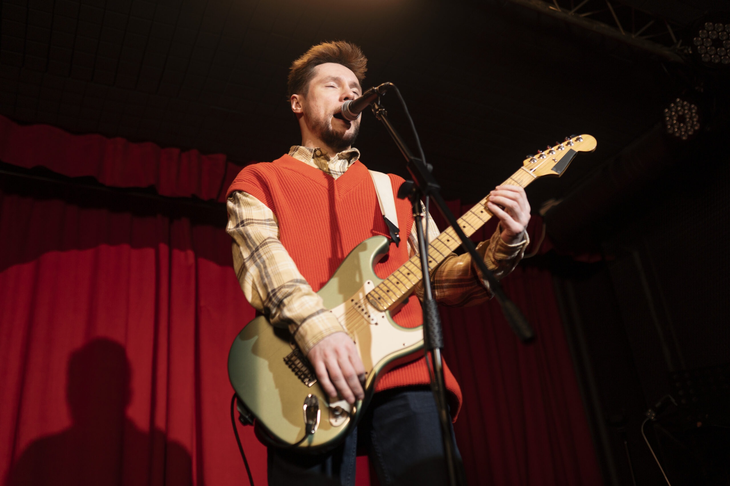Male Musician Performing on Stage While Playing an Electric Guitar