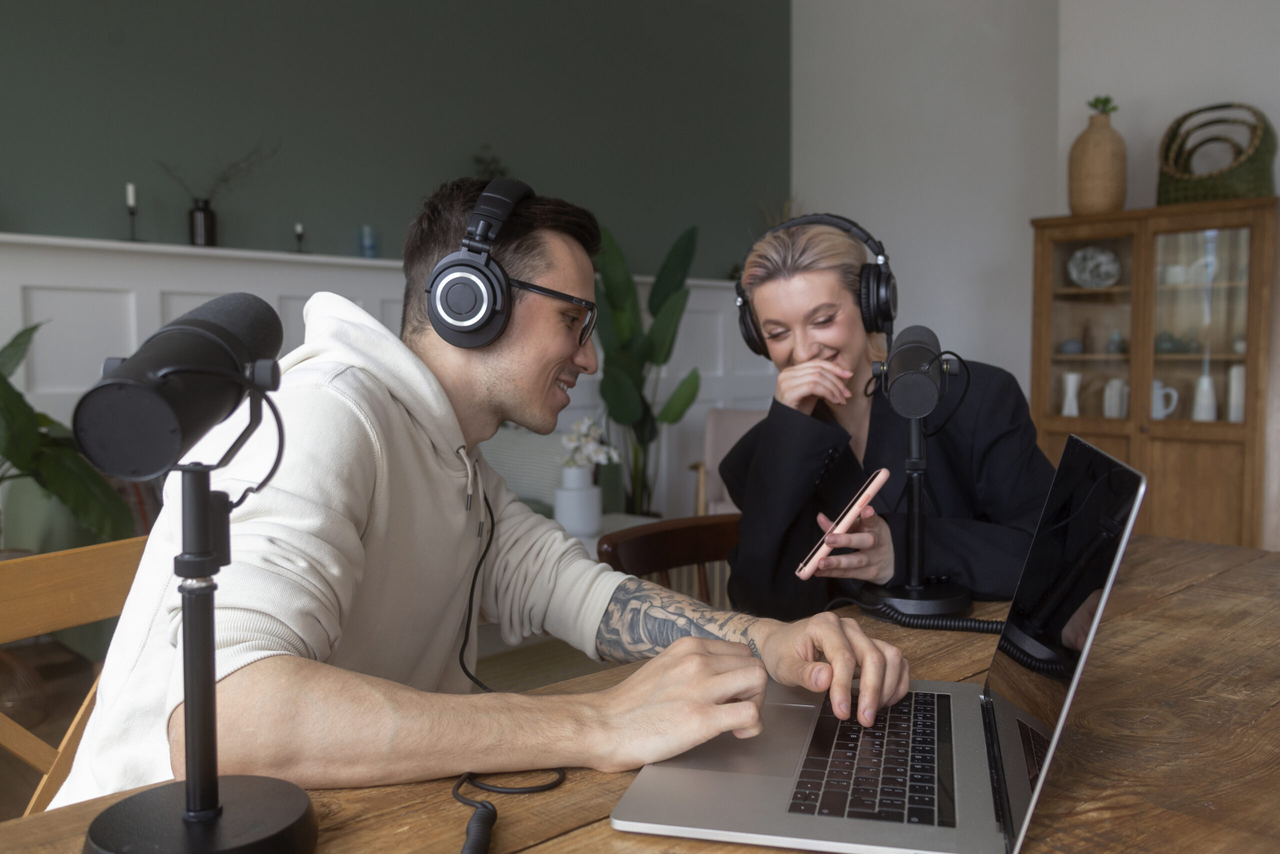 Two People Wearing Headphones Collaborating on a Laptop in a Casual Studio Setup